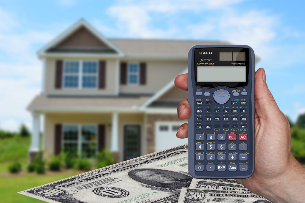 Person holding calculator with home and money in background